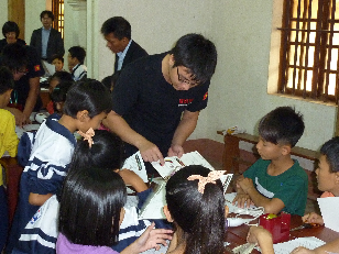 MHIVA employee instructs students on how to make a paper airplane.