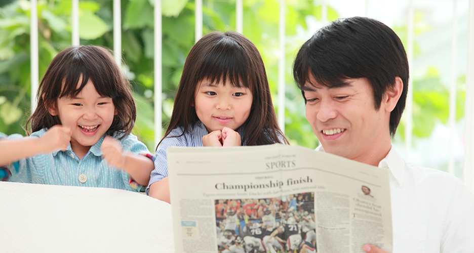 Scenic photograph of a family sharing a newspaper