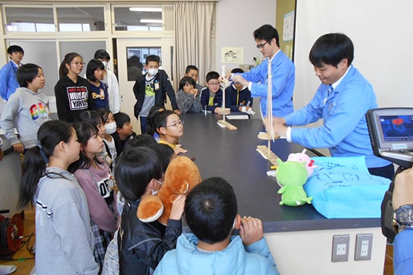 Employees demonstrating how a bow drill uses frictional heat(Nishibiwajima Elementary School)